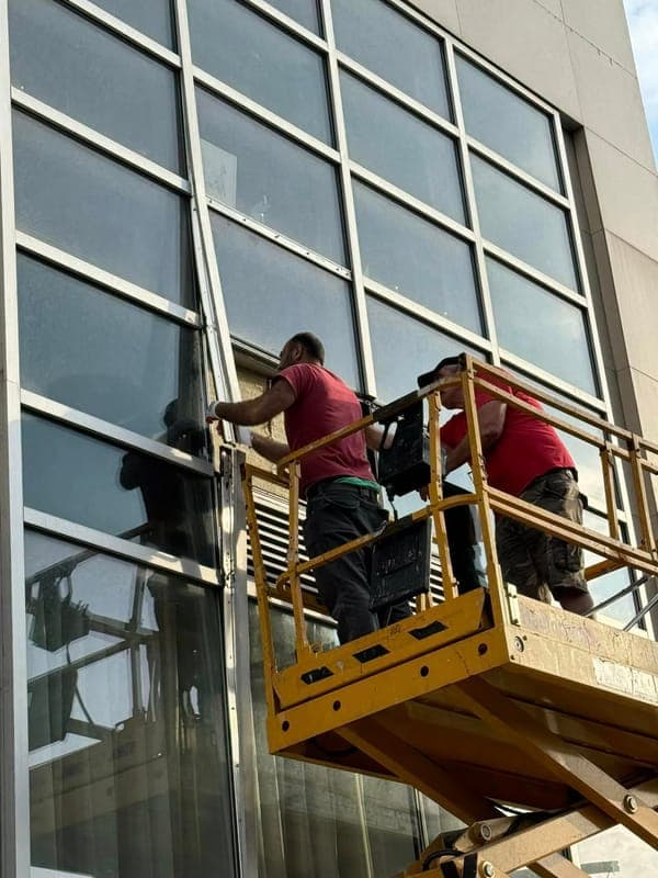 Technician servicing a glass facade from a lift